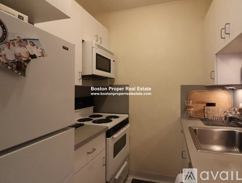 A kitchen with white appliances and a website address for Boston Proper Real Estate.