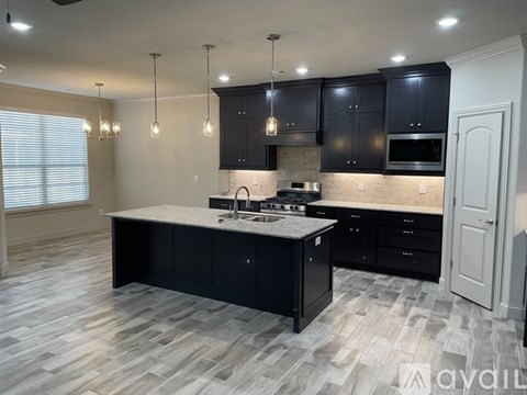 A modern kitchen with black cabinets and a marble countertop.