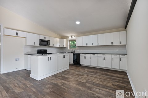 A kitchen with white cabinets and a wooden floor.