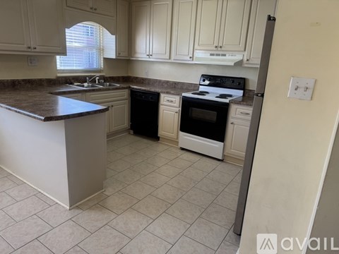 A kitchen with white cabinets and a brown countertop.