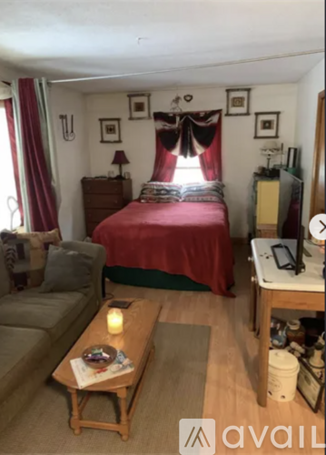 A bedroom with a bed, nightstand, and a couch.