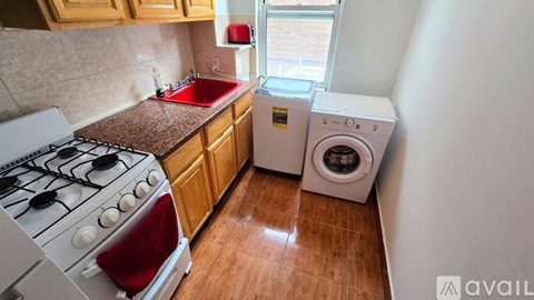 A kitchen with a red stove top and a washer and dryer stacked together.