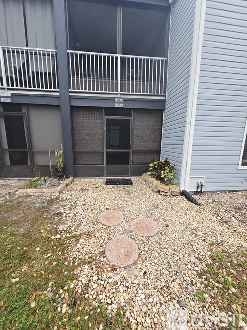 A gravel area with three circles on it and a building in the background.