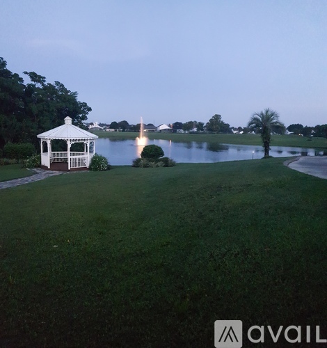 A gazebo sits on a lawn by a lake.