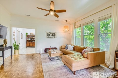 A living room with a tan couch and a ceiling fan.