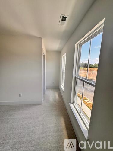 A room with a window showing a view of a road and trees.