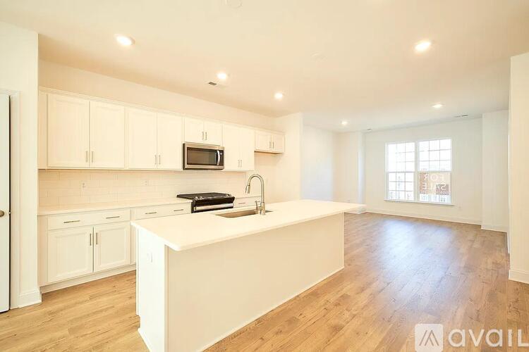 A kitchen with white cabinets and a white island with a sink.