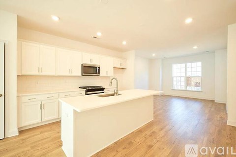 A kitchen with white cabinets and a white island with a sink.