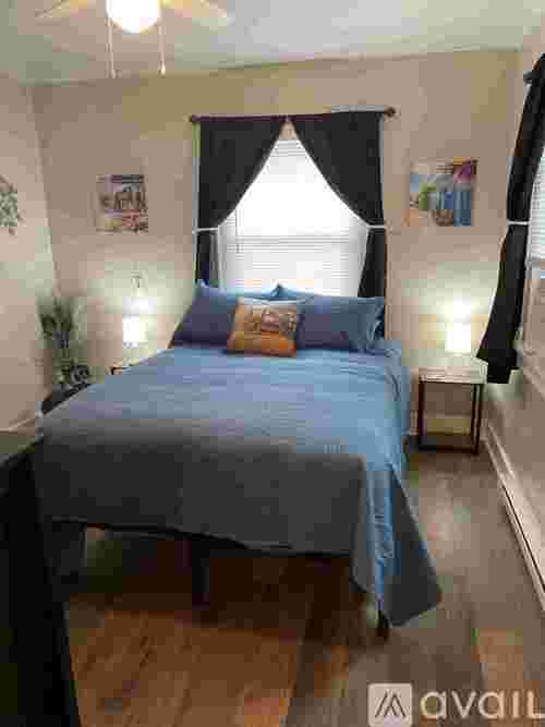 A bedroom with a bed covered in a blue sheet and a pillow on it.