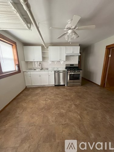 A kitchen with a fan and a brown floor.