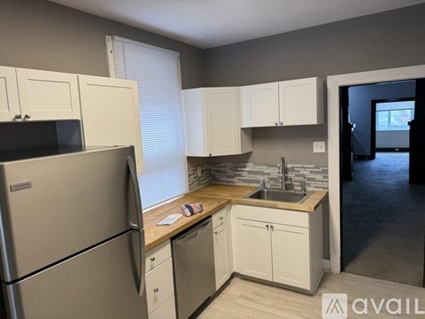 A kitchen with a refrigerator, cabinets, and a sink.