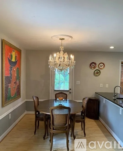 A dining room with a chandelier, a table with chairs, and a painting on the wall.