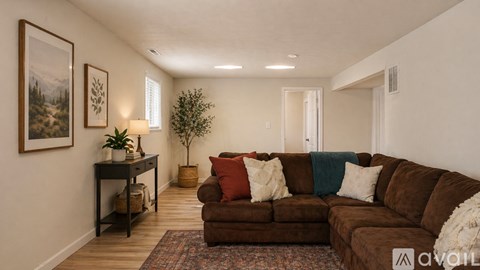 A living room with a brown couch and a small table with a plant on it.