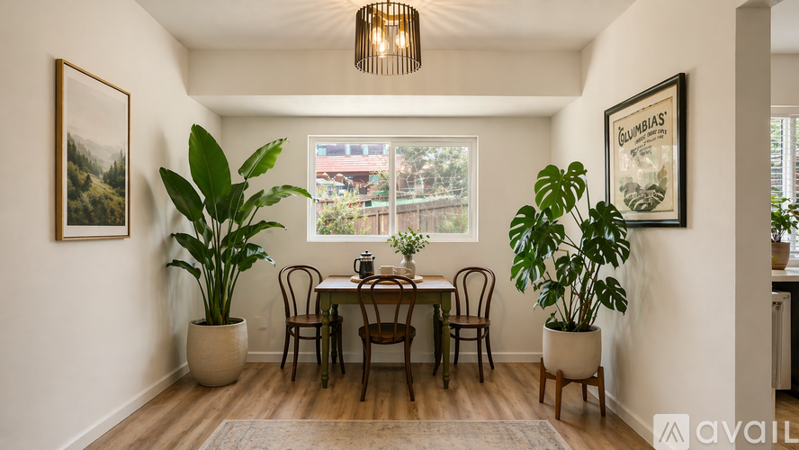 A dining room with a table set for four and a view of a backyard through the window.