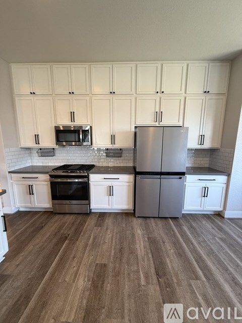 A kitchen with white cabinets and a wooden floor.