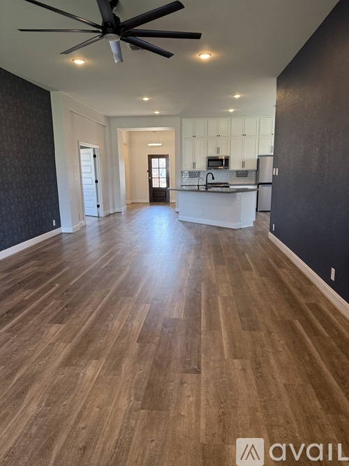 A spacious room with wooden flooring and a ceiling fan.