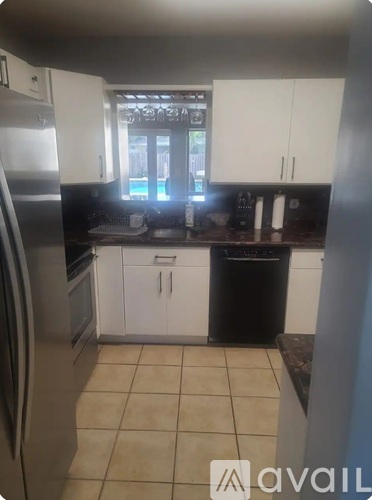 A kitchen with white cabinets and a black dishwasher.