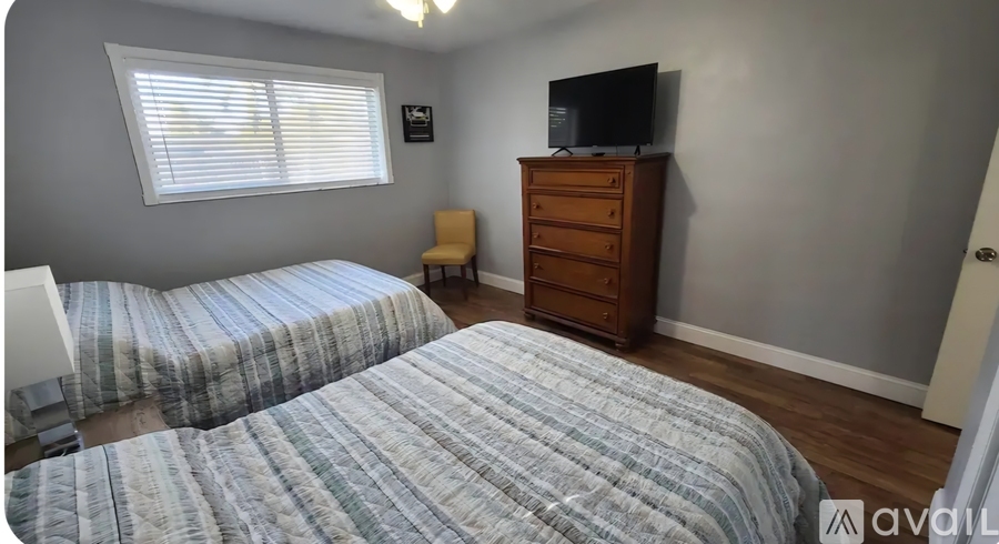 A bedroom with two beds and a television on a dresser.