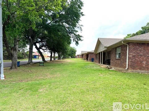 A grassy area with trees and a building in the background.