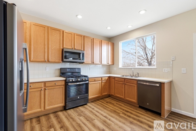 A kitchen with wooden cabinets and a black refrigerator.