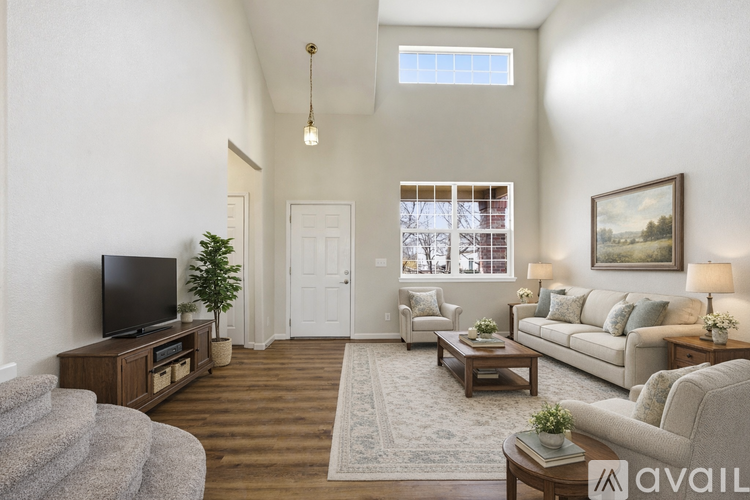 A living room with a grey couch, a wooden coffee table, a television, and a painting on the wall.