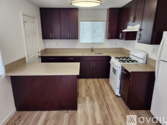 A kitchen with dark wood cabinets and a white stove top oven.