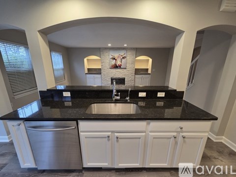 A kitchen with a black countertop and white cabinets.