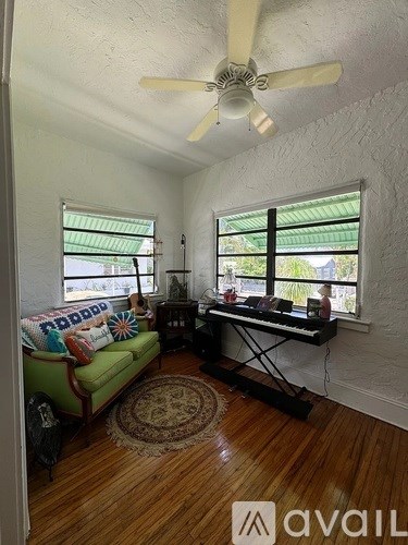 A living room with a green couch and a piano.