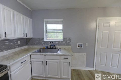 A kitchen with white cabinets and a marble countertop.