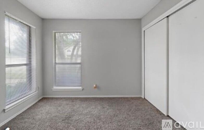 A room with a carpeted floor and a window with blinds.