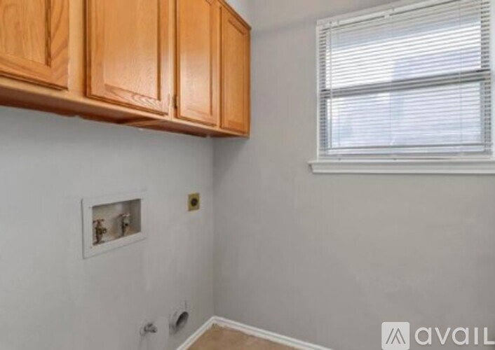 A room with wooden cabinets and a window with blinds.
