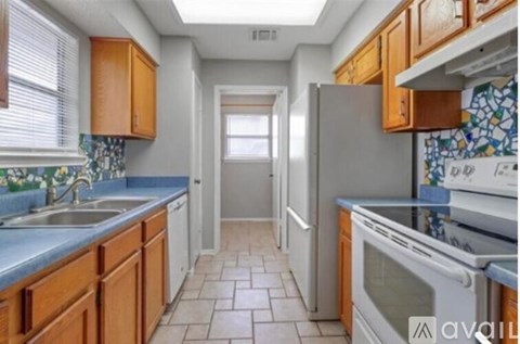 A kitchen with wooden cabinets and tile flooring.