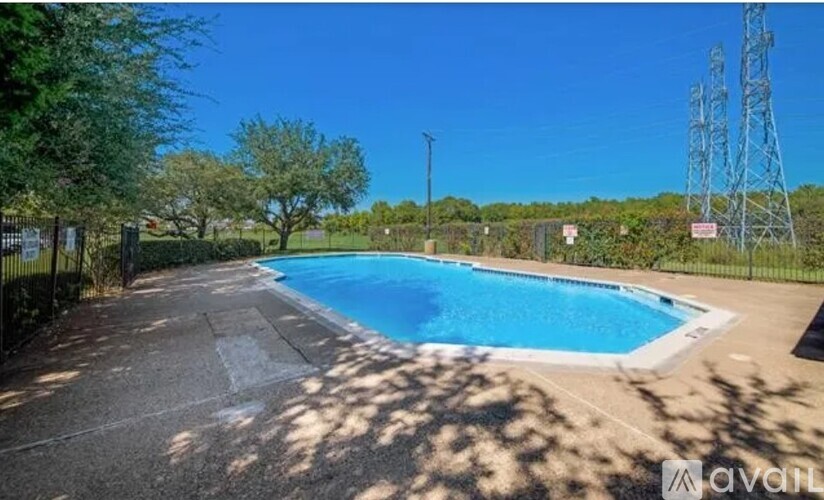 A pool surrounded by a fence with trees and a tower in the background.