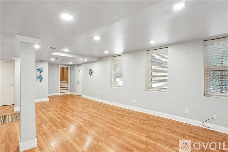A spacious room with wooden flooring and white walls.