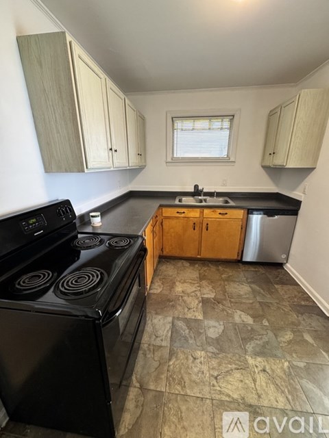 A kitchen with a black stove top oven and wooden cabinets.