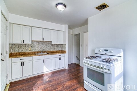 A kitchen with white cabinets and a stove top oven.