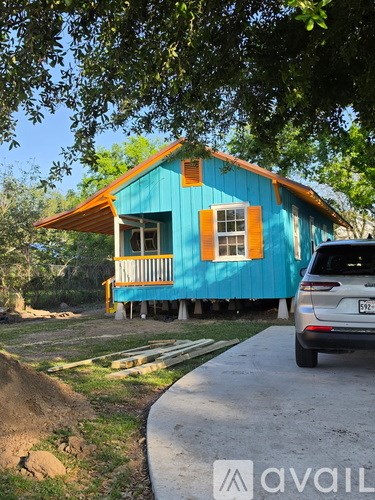 A blue house with orange trim and a car parked in front.