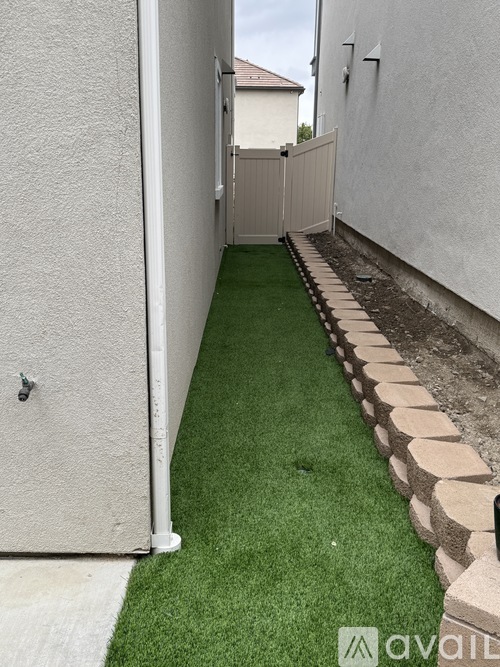 A narrow alley with a green artificial grass strip down the middle.