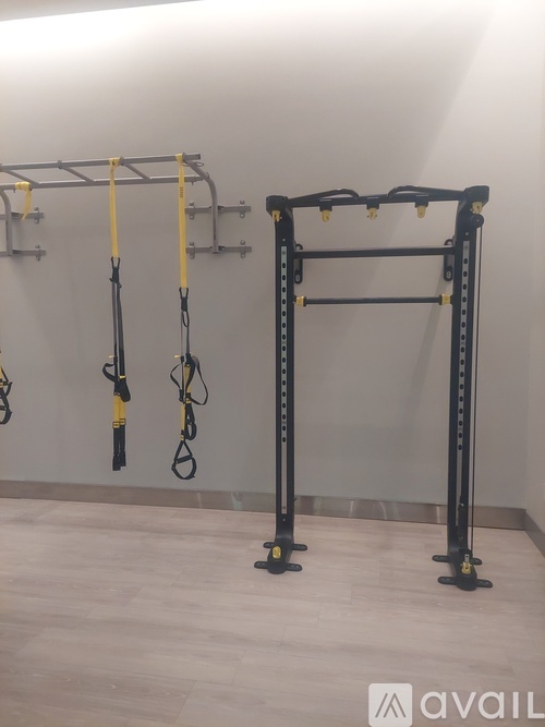 A gym with a wall-mounted pull up bar and a squat rack.
