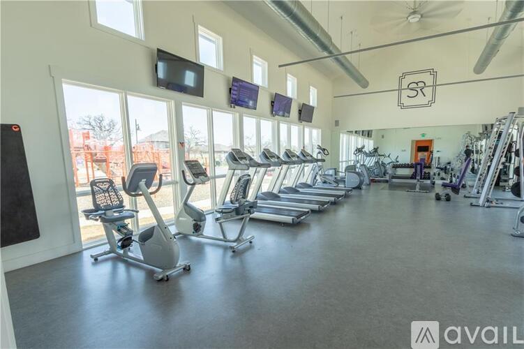 A gym with a row of treadmills and elliptical machines.