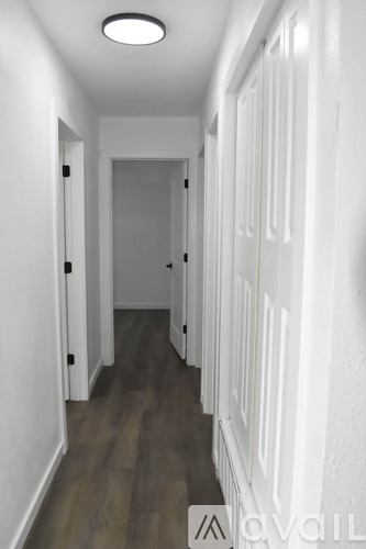 A long hallway with white walls and wood flooring.