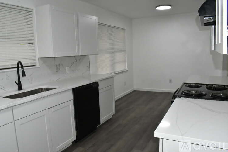 A kitchen with white cabinets and a black dishwasher.