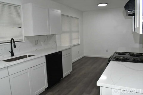 A kitchen with white cabinets and a black dishwasher.