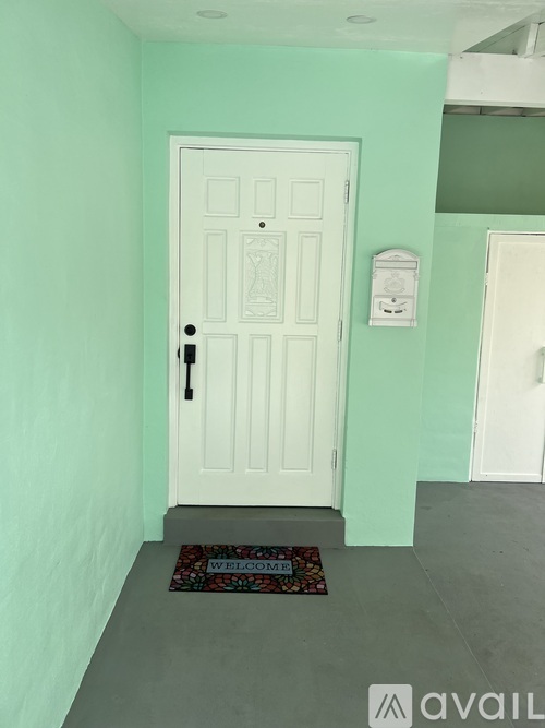 A white door with a black handle and a doormat that says "welcome".