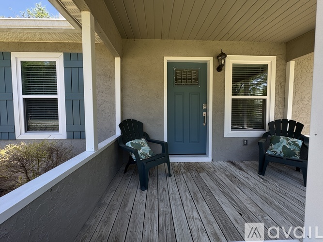 A porch with two chairs and a door.