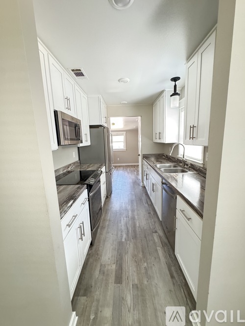 A kitchen with white cabinets and a grey floor.