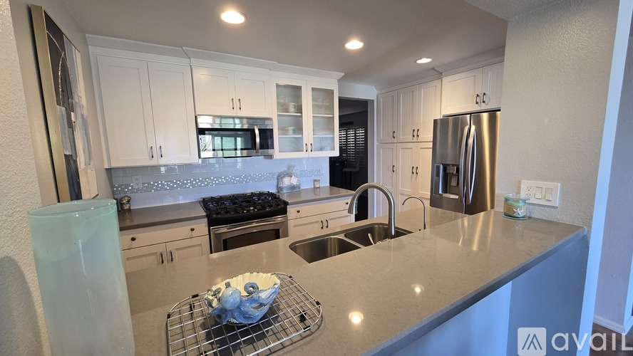 A kitchen with white cabinets and a stainless steel refrigerator.