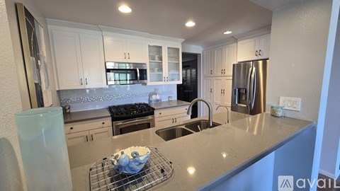 A kitchen with white cabinets and a stainless steel refrigerator.
