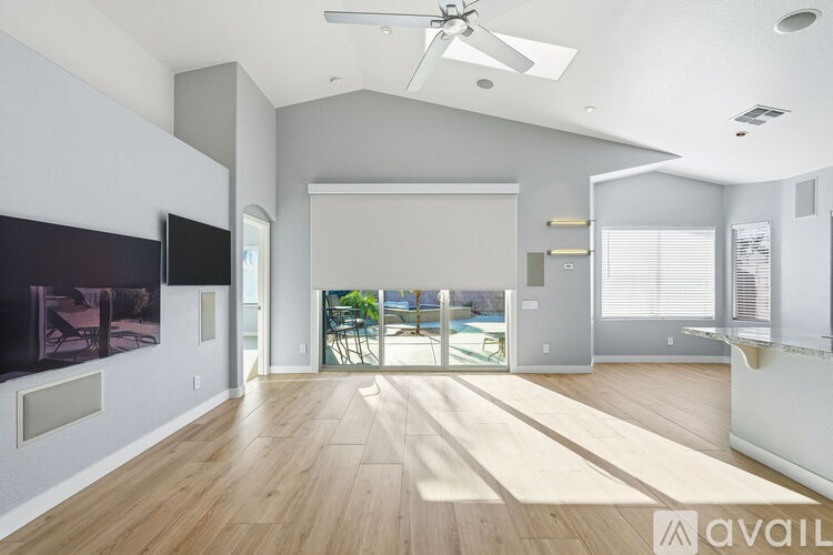 A spacious living room with a television and sliding glass doors leading to a balcony.
