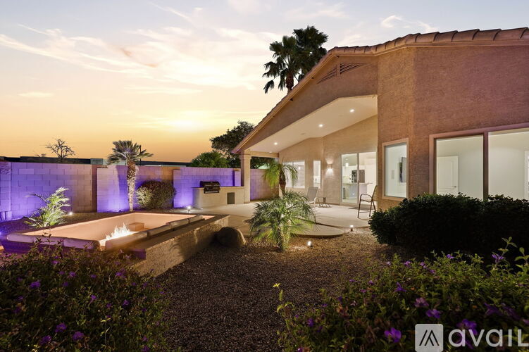 A modern house with a garden and a pool at dusk.